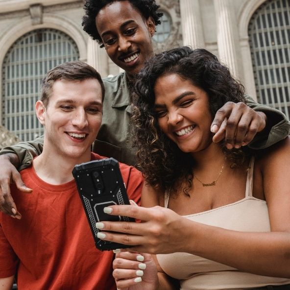 Junge Menschen schauen glücklich auf ein Smartphone