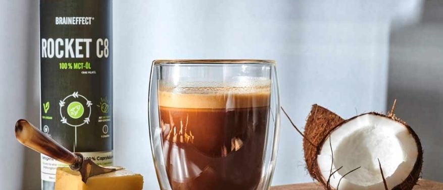 ROCKET C8 Öl von BRAINEFFECT neben Glas mit Butter Kaffee und einer Kokosnuss