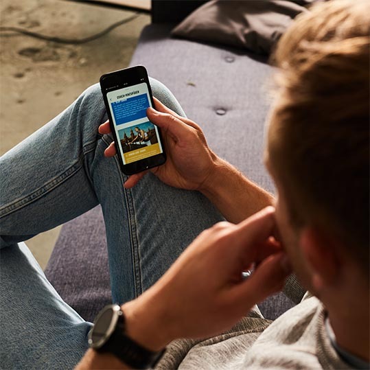 Mann sitzt mit Smartphone auf Sofa